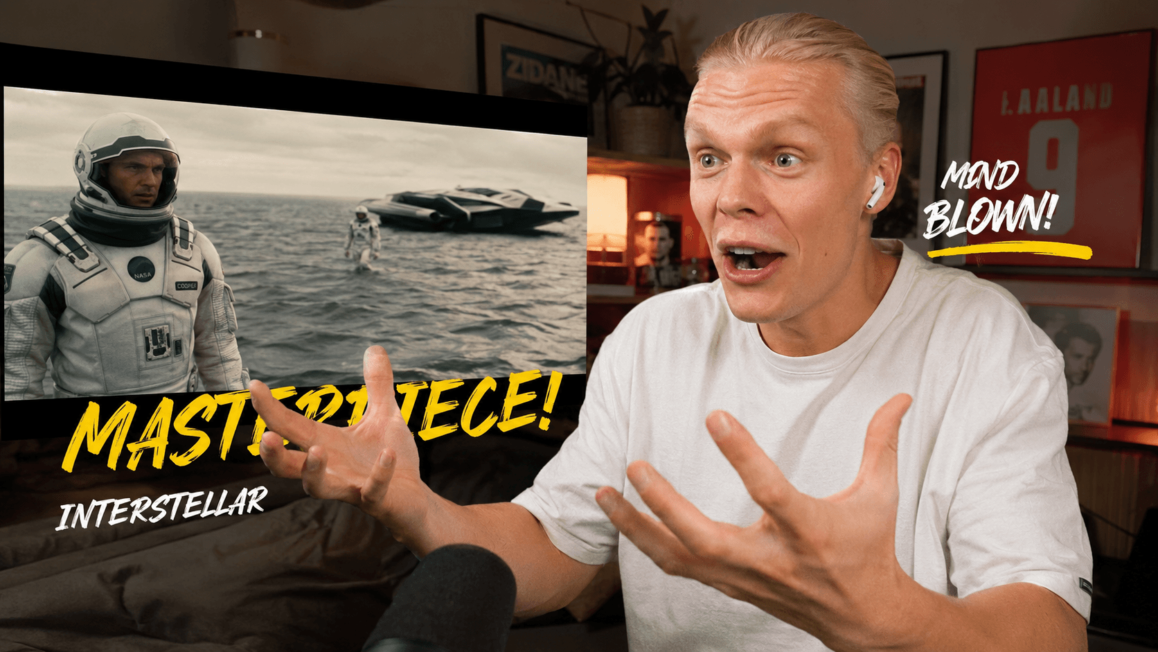 Couple on a couch reacting in shock to a film on a large screen while a camera on a tripod records them
